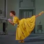 A screenshot from An American in Paris; Leslie Caron in a yellow dress performing an arabesque.